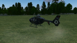 EC135 hovering near a forest