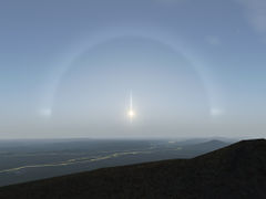 Sun halo (22 degree ring), Sun pillar (vertical line through the sun), and Sun dogs (left and right of the sun).
