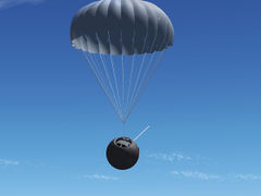 The charred capsule hanging underneath the braking parachute